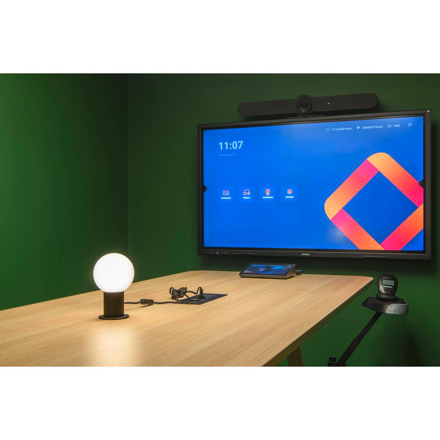 Lampe posée sur un bureau devant un grand écran, pièce verte