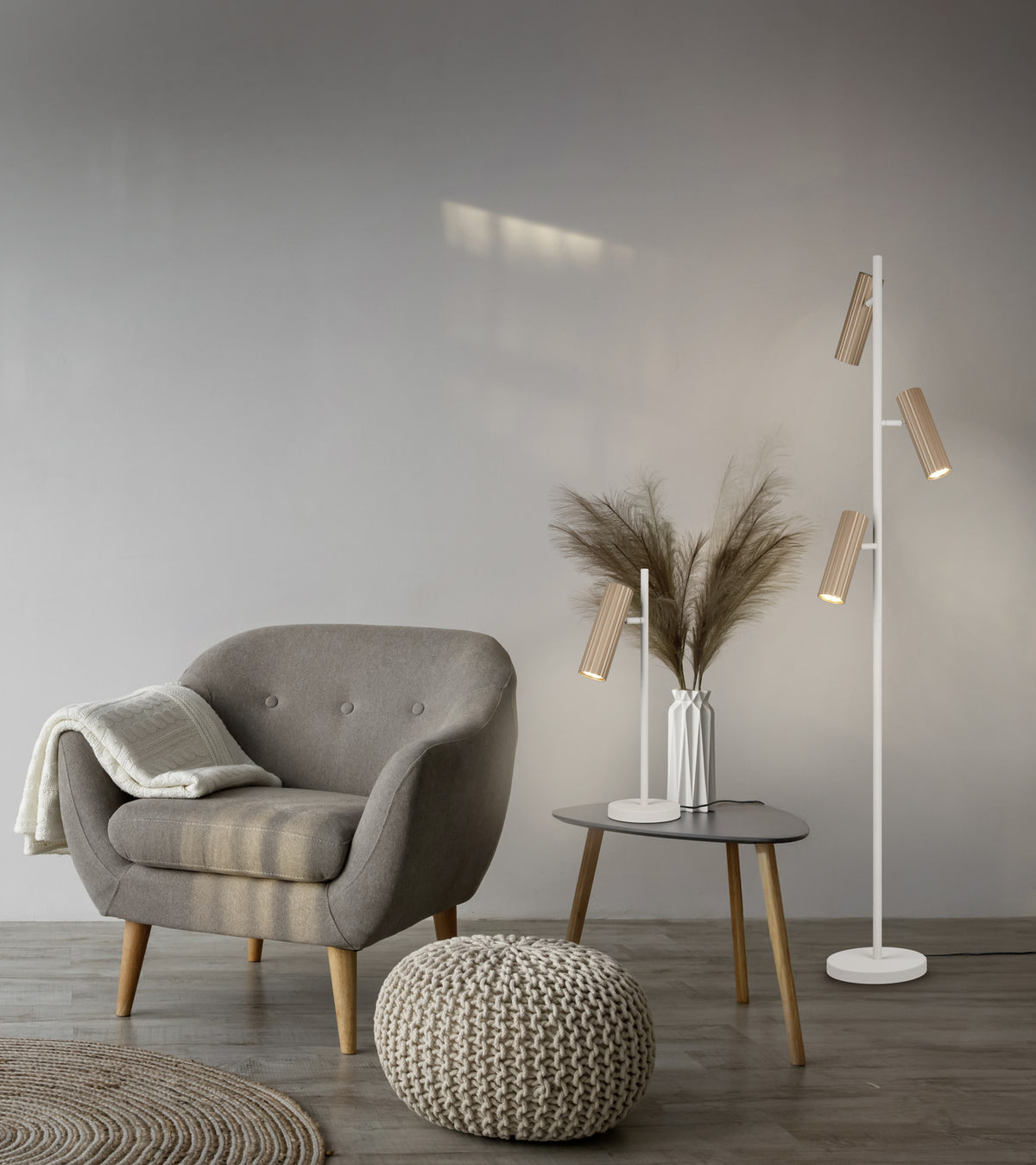 Mise en ambiance salon : lampadaire allumé près d'un fauteuil gris et d'une table basse