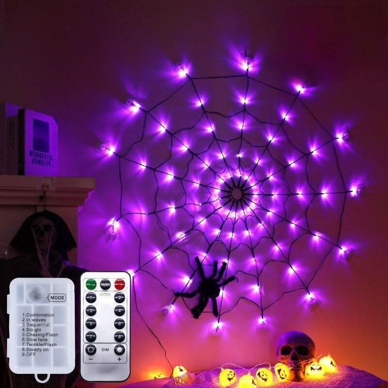 Toile violette fixée au mur, télécommande et boîtier à piles présentés, citrouilles et crâne décoratifs